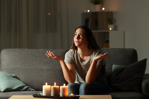 Woman complaining during a blackout sitting on a couch in the living room at home - Fotoğraf, Görsel