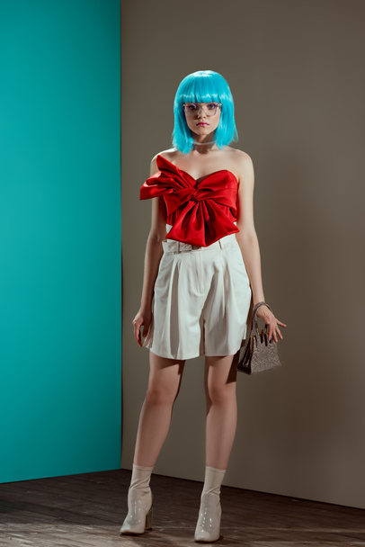 full length view of beautiful stylish girl in blue wig looking at camera in studio  - Foto, afbeelding