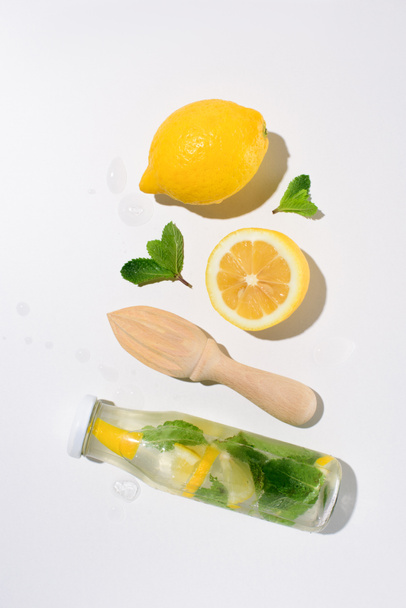 Widok z góry z cytryny, liście mięty, drewniane wyciskacz i butelkę lemoniady  - Zdjęcie, obraz