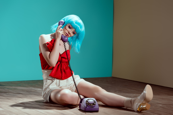 beautiful stylish female model sitting on floor and talking by rotary phone - Фото, изображение