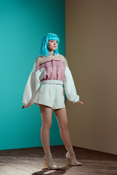 full length view of fashionable female model in blue wig posing and looking away in studio - Photo, Image