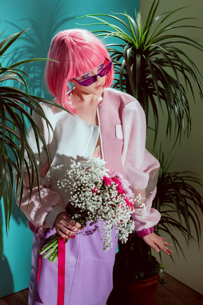 high angle view of fashionable girl in pink wig holding bouquet of flowers and looking away - Fotoğraf, Görsel