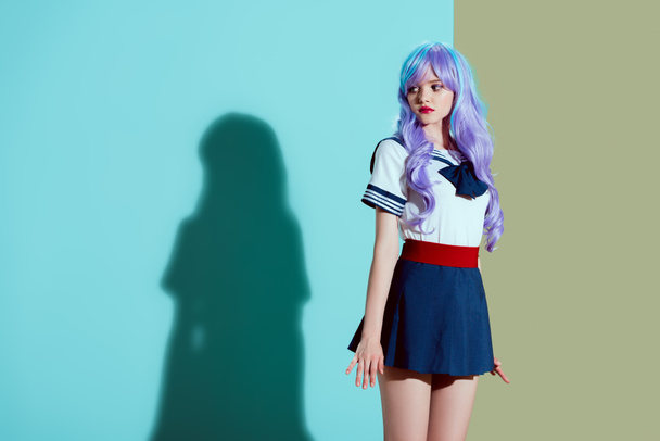 beautiful girl in bright wig and skirt standing and looking away in studio - 写真・画像