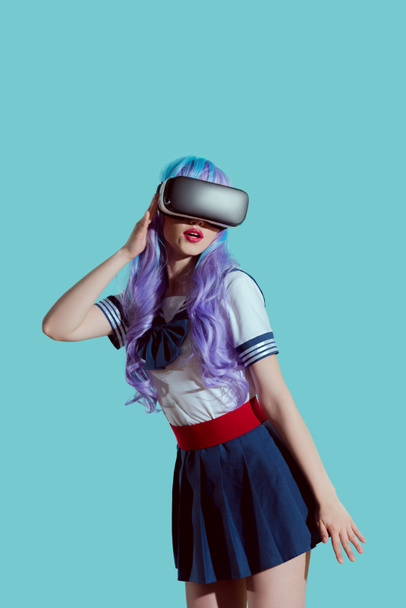 青に分離された仮想現実のヘッドセットを使用して紫のウィッグでスタイリッシュな女の子  - 写真・画像