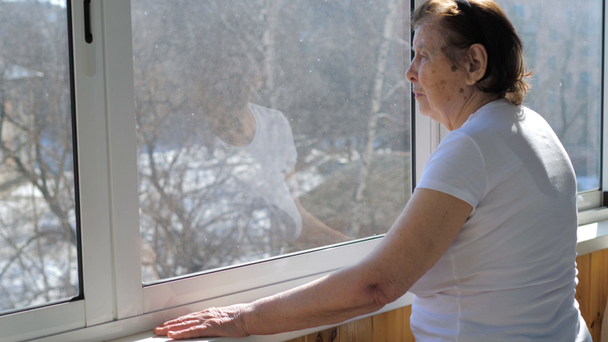 Une femme âgée debout à la fenêtre et regardant la rue
 - Séquence, vidéo