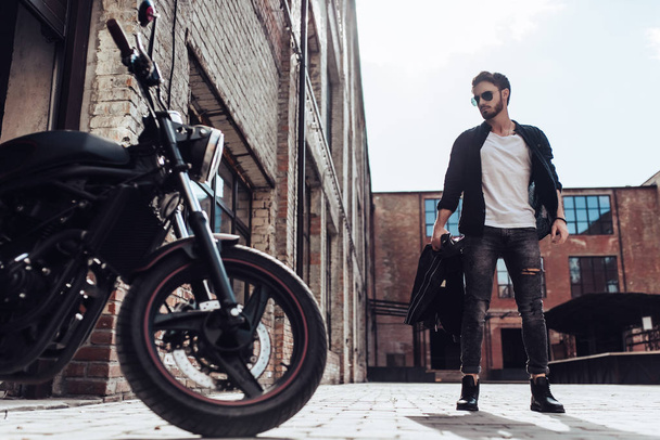 Handsome bearded biker with classic style black motorcycle. Cafe racer. - Fotoğraf, Görsel