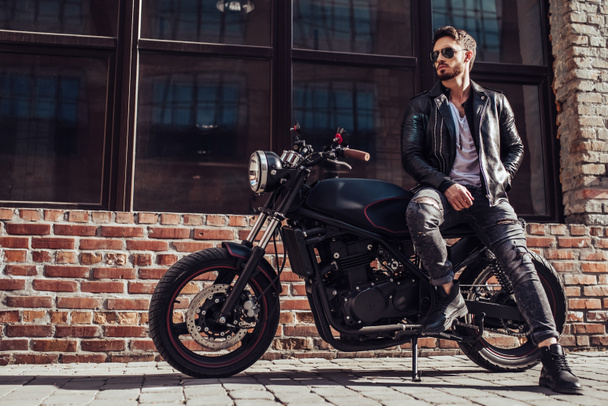 Handsome bearded biker with classic style black motorcycle. Cafe racer. - Fotografie, Obrázek