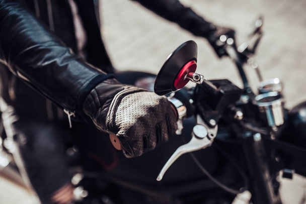 Imagem recortada de motociclista barbudo bonito com motocicleta preta estilo clássico. Café piloto
. - Foto, Imagem