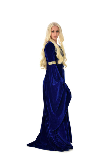 青いファンタジー中世ドレスを着てかなりブロンドの女性の完全な長さの肖像画。白い背景の上の立ちポーズ. - 写真・画像