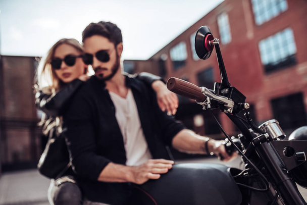 Romantic biker couple with black motorcycle. Handsome bearded man and young attractive woman outdoors with cafe racer. - Fotoğraf, Görsel