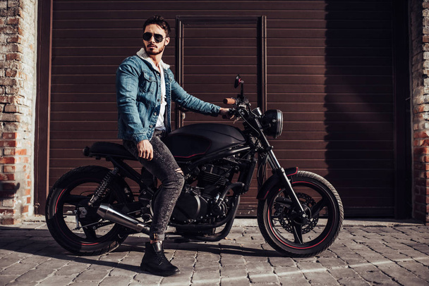 Handsome bearded biker with classic style black motorcycle. Cafe racer. - Foto, Imagem
