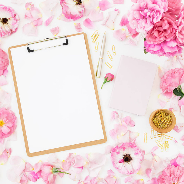 Top view of notebook and pen on pastel pink background with flowers - Фото, изображение