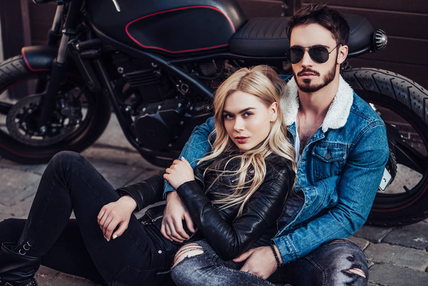 Romantic biker couple with black motorcycle. Handsome bearded man and young attractive woman outdoors with cafe racer. - Foto, Imagem