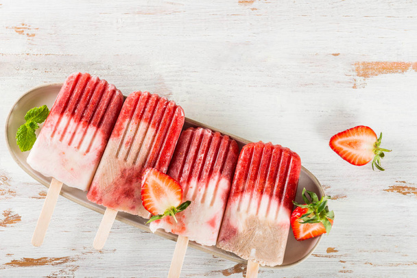 Homemade Vegan Strawberry Popsicle from Strawberry Juice and Coconut Milk on light wooden background. Summer food concept. Top view. - Photo, image