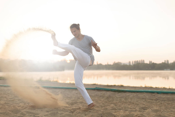 Athletic capoeira performer workout training on the beach sunris - Photo, Image