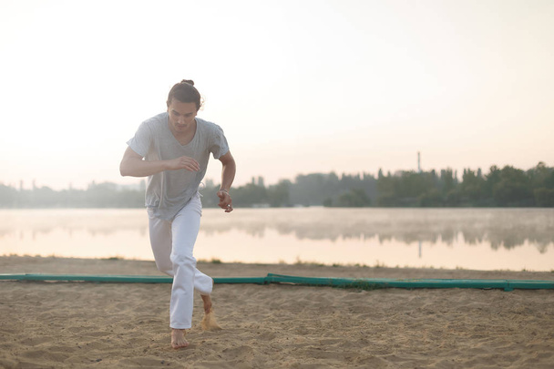 Athletic capoeira performer making movements on the beach - Valokuva, kuva