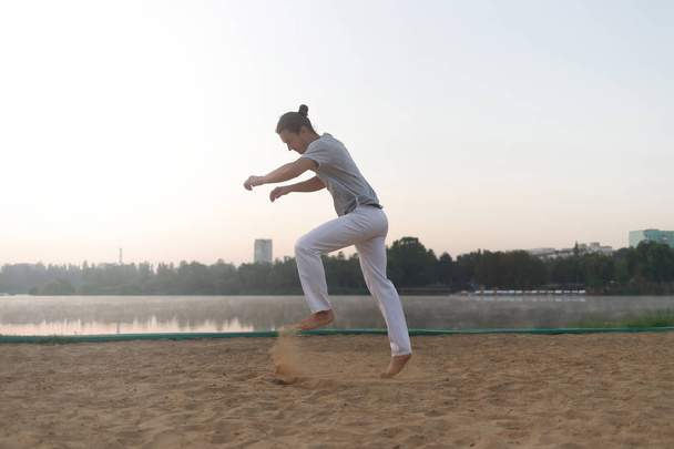 Спортивный человек готовится к прыжку на пляж во время тренировки
 - Фото, изображение