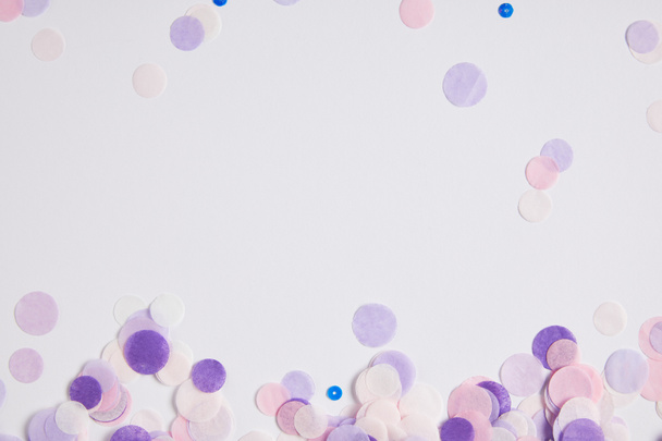 vue de dessus des morceaux de confettis violets dispersés sur la surface blanche
 - Photo, image