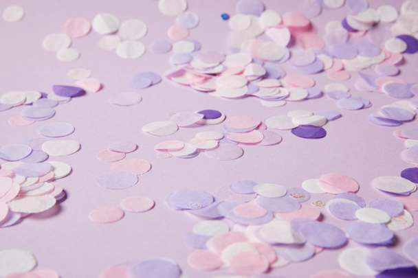 Selektiver Fokus von Konfettistücken auf violette Oberfläche - Foto, Bild
