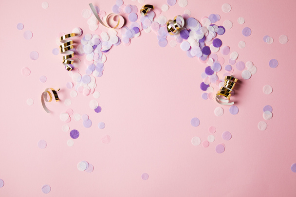 vista elevada de piezas de confeti violeta en la superficie rosa
 - Foto, Imagen