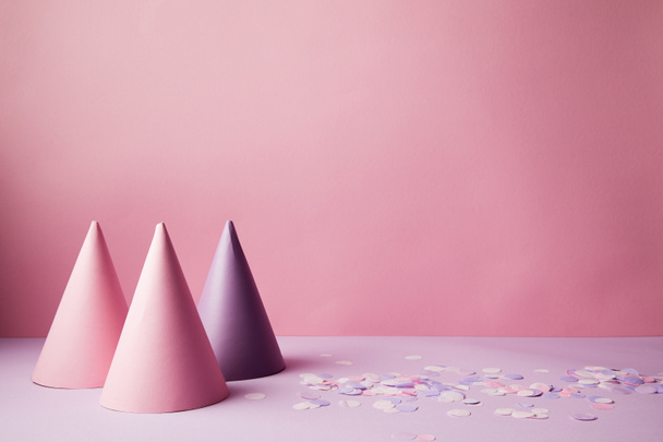 sombreros de fiesta rosa y violeta y piezas de confeti en la superficie violeta
 - Foto, Imagen
