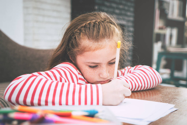 Kid Girl oturma odasında kağıt üzerine kalem boyuyor. - Fotoğraf, Görsel