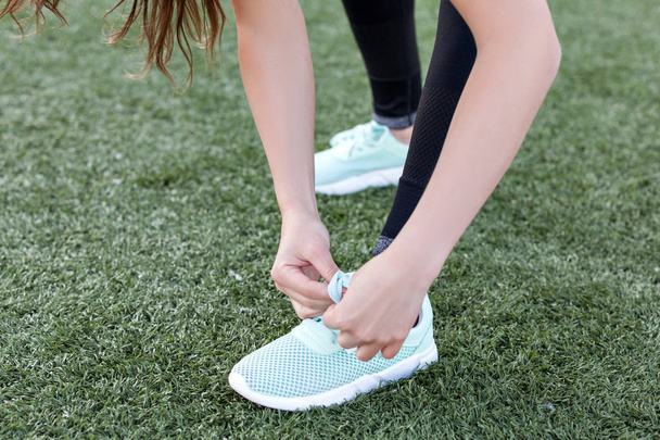 Во время тренировки спортсменка завязывает шнурки на кроссовках
. - Фото, изображение