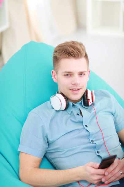 A young handsome man on the couch listening to music - Foto, immagini