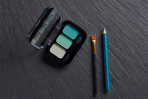 Eye shadows in blue tones with pencil and brush on dark slate background - Photo, Image