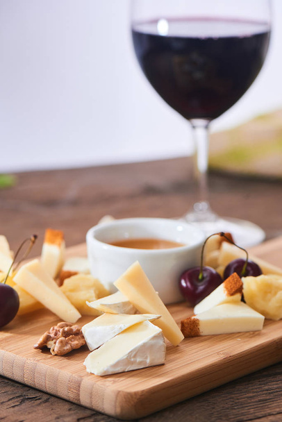 set of parmesan with mozzarella and camembert cheeses with glass of red wine on wooden board - 写真・画像