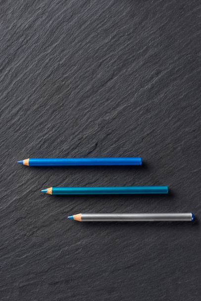 Μακιγιάζ μολύβια σε μπλε αποχρώσεις στο σκούρο φόντο πλακών - Φωτογραφία, εικόνα
