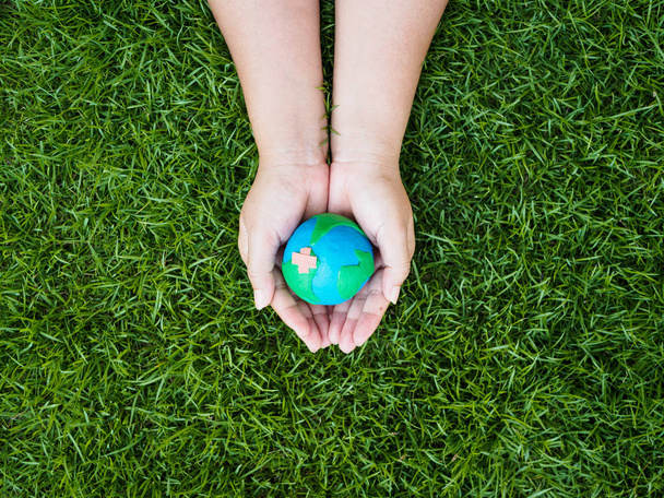 earth day. earth in hands and green grass field background. environment save earth concept. - Photo, Image