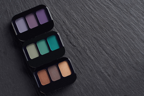 Makeup palettes in a row on dark slate background - Foto, afbeelding