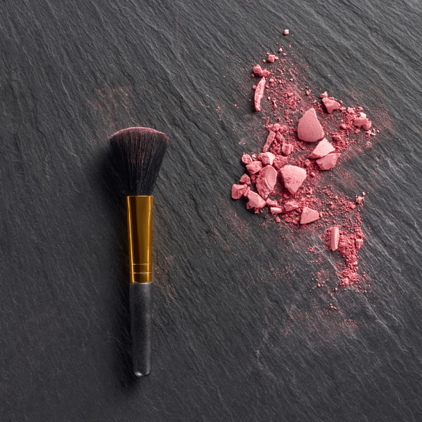 Pink blush pieces and brush on dark slate background - Photo, Image