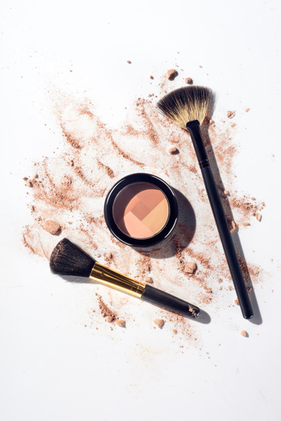 Pressed contouring powder with brushes on white background with scattered foundation - Photo, Image