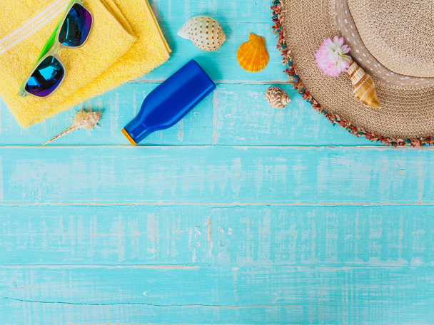ビーチ アクセサリーは日焼け止めや帽子ビーチ、シェルなど、黄色のタオルとレトロなカメラに明るい青夏の休日や休暇の概念のパステル調の木製の背景. - 写真・画像