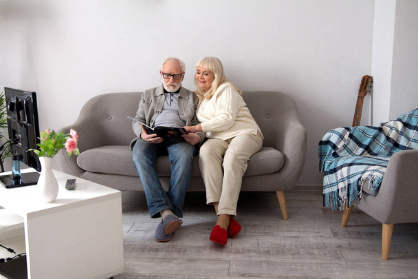 Elderly couple reading on couch. - 写真・画像