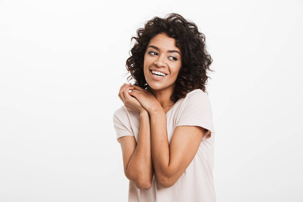 Porträt einer schönen Amerikanerin in Jeans und T-Shirt, die die Arme vor der Brust zusammenhält und isoliert über weißem Hintergrund lächelt - Foto, Bild