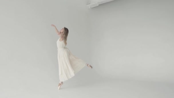 елегантна та витончена балерина танцює у білій літаючій сукні та взутті на білому тлі. повільний рух
 - Кадри, відео