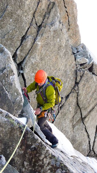 escalador de montaña macho atraviesa una chimenea de roca difícil en su camino a una alta cumbre alpina
 - Foto, imagen