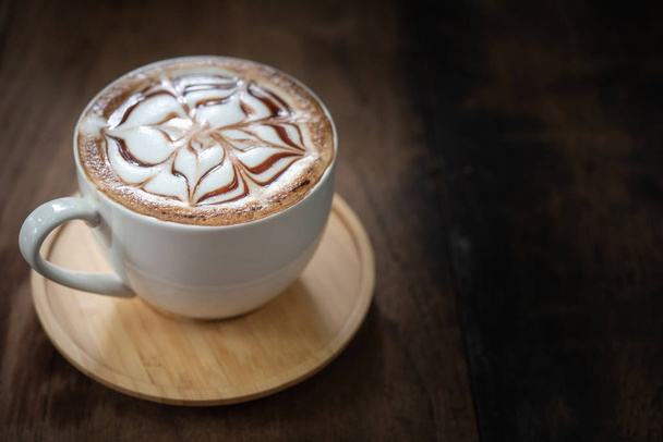Tasse Kaffee auf schwarzem rustikalem Hintergrund mit schöner Latte-Art. Tasse Kaffee auf einem Holztisch - Foto, Bild