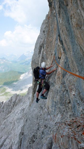 miespuolinen vuorikiipeilijä jyrkällä kalliokiipeilyreitillä Sveitsin Alpeilla lähellä Klostersia
 - Valokuva, kuva