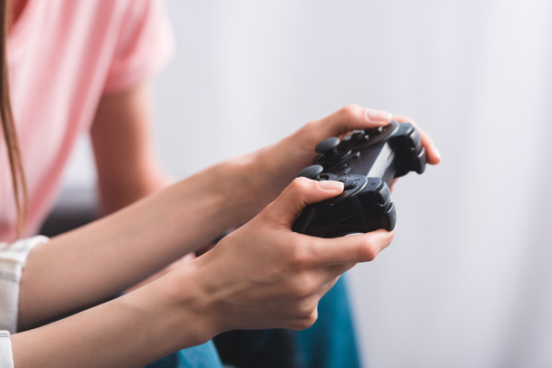 cropped image of woman holding joystick and playing video game with friend  - Foto, afbeelding