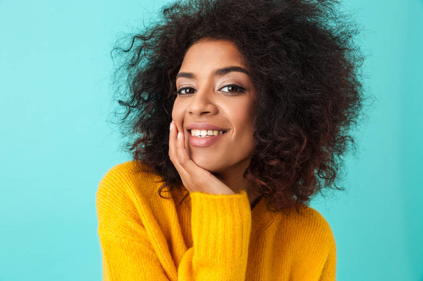 Multicolor portrait of splendid curly woman in yellow shirt looking on camera with smile while propping her head isolated over blue background - Zdjęcie, obraz