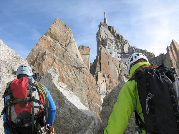 mountain guide and a male client on a rocky ridge heading towards a high summit in the French Alps near Chamonix - Foto, immagini
