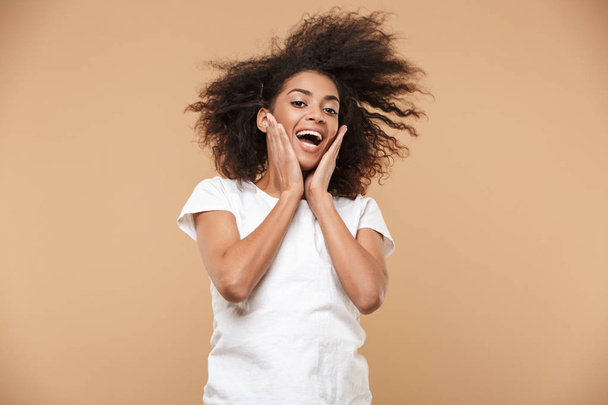 Portrait of a shocked young african woman celebrating success isolated over beige background - Valokuva, kuva