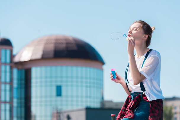 mujer joven usando soplador de burbujas en la azotea
  - Foto, imagen