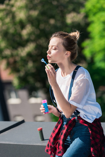 atractiva joven mujer usando soplador de burbujas en la azotea
  - Foto, imagen