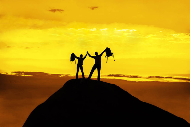 siluetti onnellinen pari seisoo yhdessä huipulla vuoren kädet ylhäällä
  - Valokuva, kuva