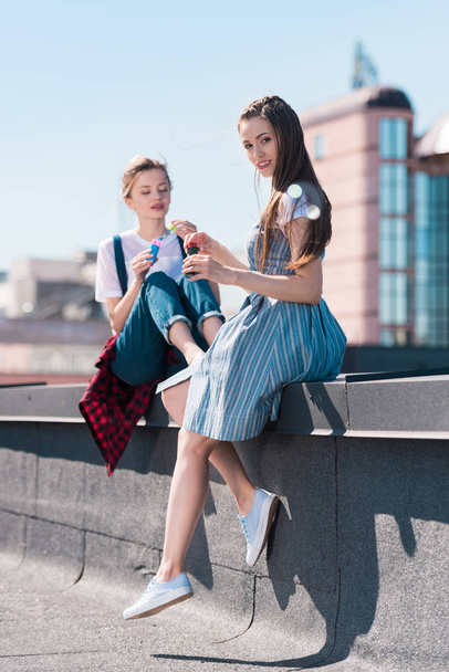 two young female friends using bubble blowers at rooftop  - Foto, Imagen